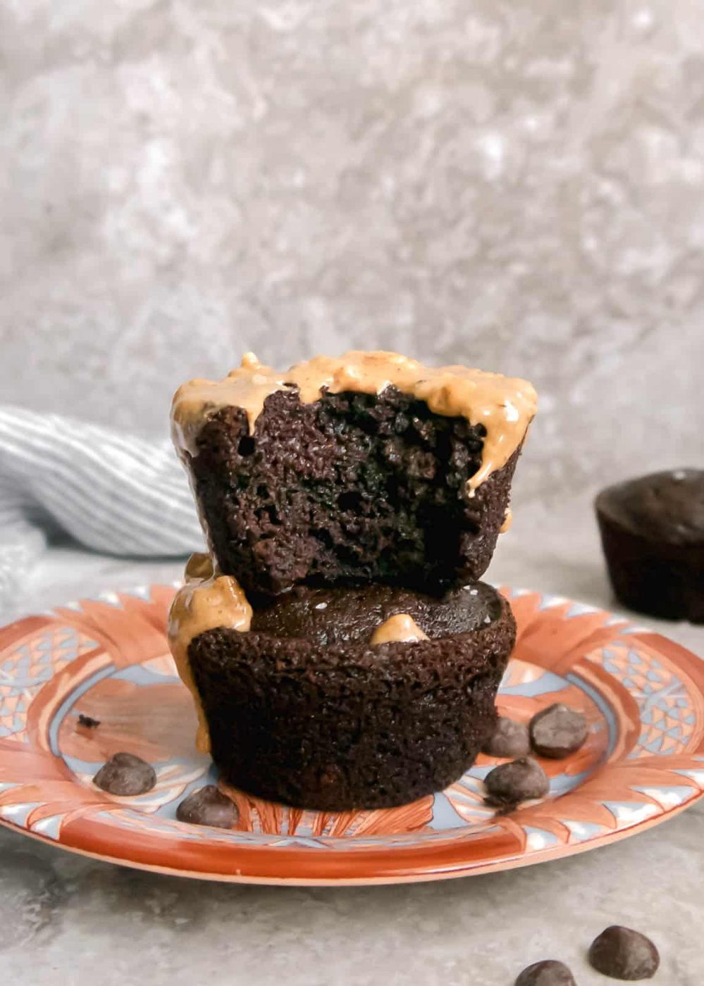 Gluten free double chocolate muffins stacked on top of each other with a bite taken out of the top one.