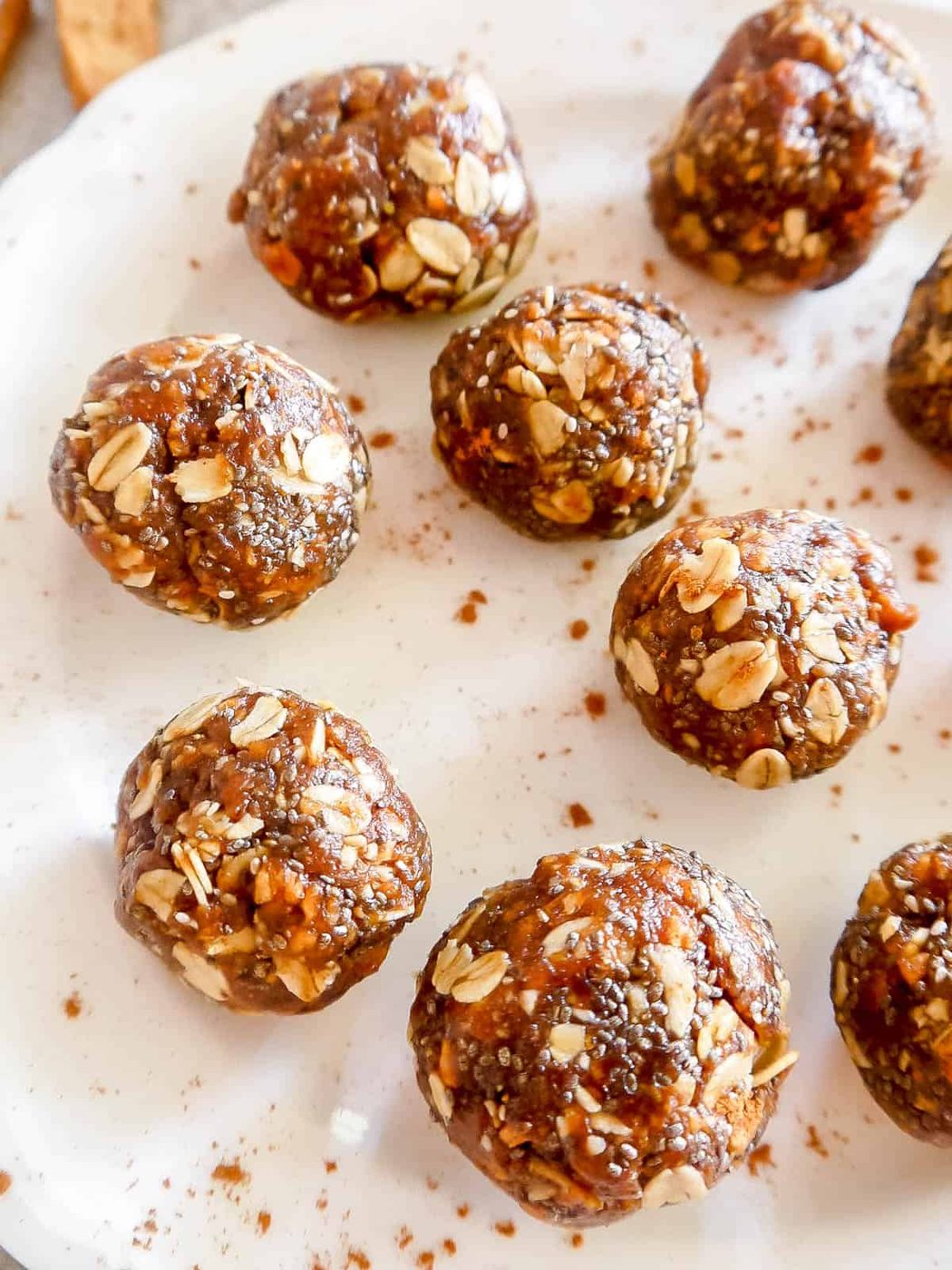 Apple pie energy balls on a plate with cinnamon sprinkled on top.