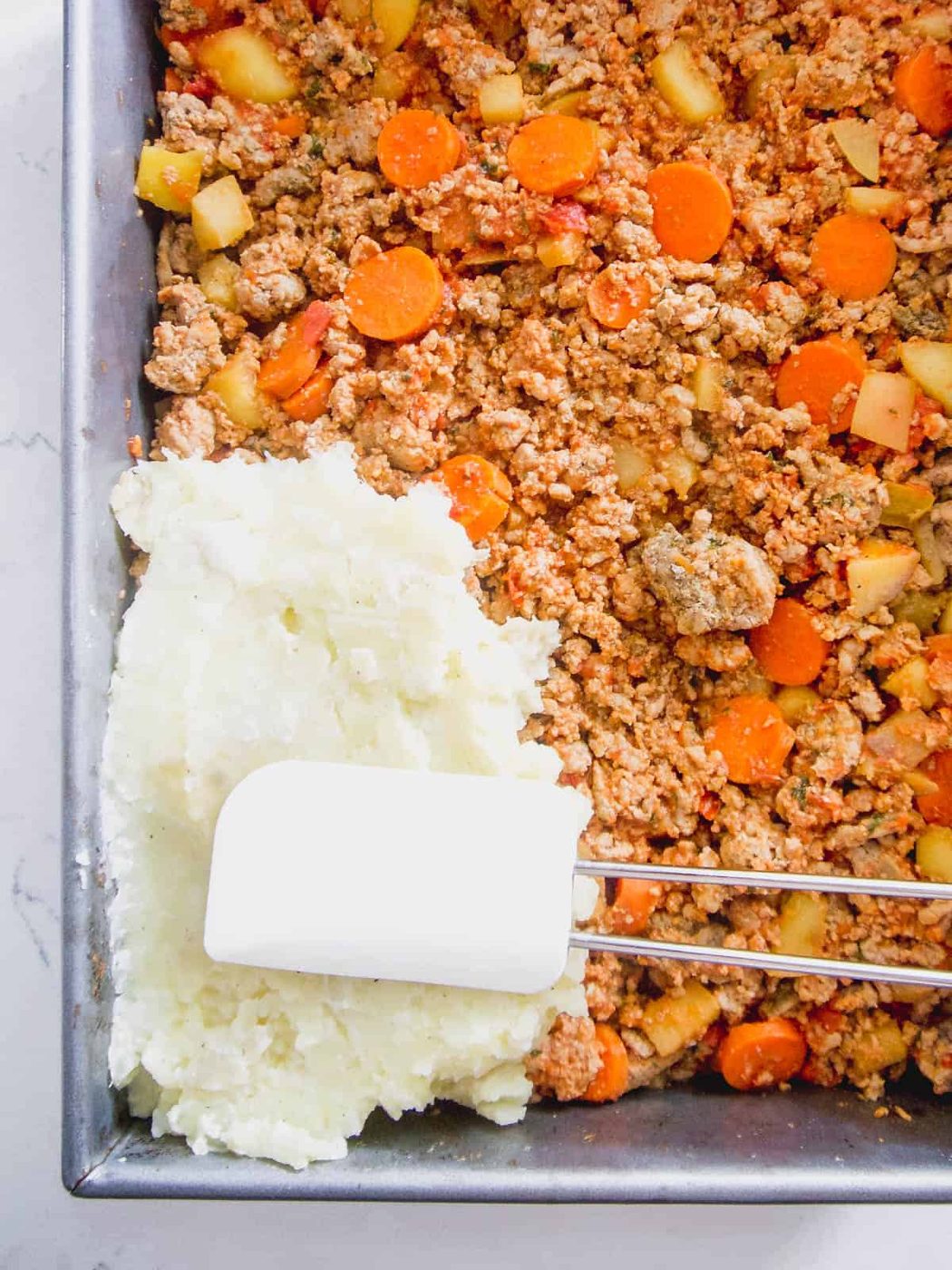 Mashed potatoes being added to the meat.