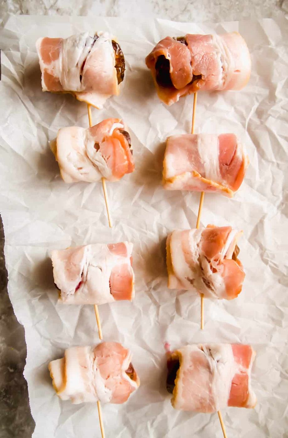 Raw bacon wrapping the raspberry stuffed dates before cooking.