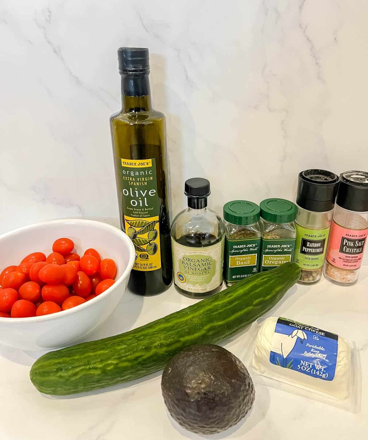 Ingredients needed to make avocado cucumber tomato salad with goat cheese.
