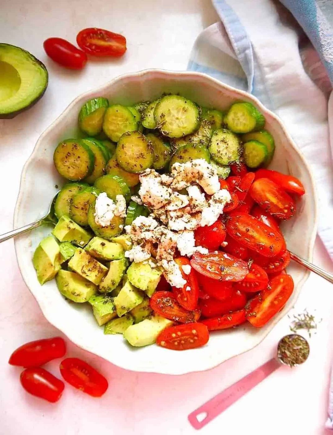 Cucumber goat cheese salad with avocado and tomatoes in a bowl.
