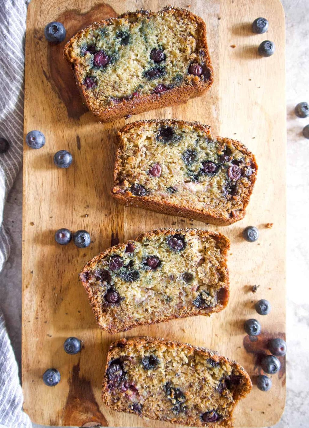 Slices of blueberry banana bread with greek yogurt on a cutting board.