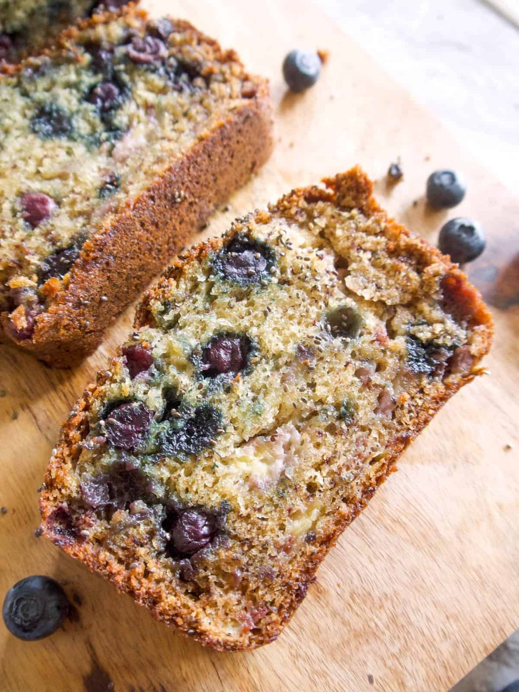 One slice of lighter banana blueberry bread on a table.