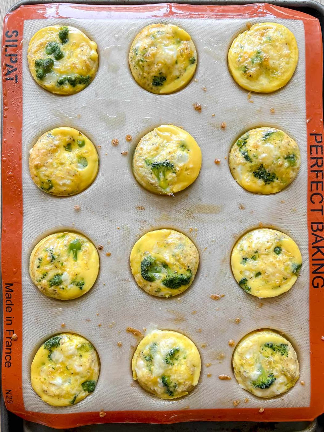 Freshly baked broccoli cheddar egg muffins in silicone tins.