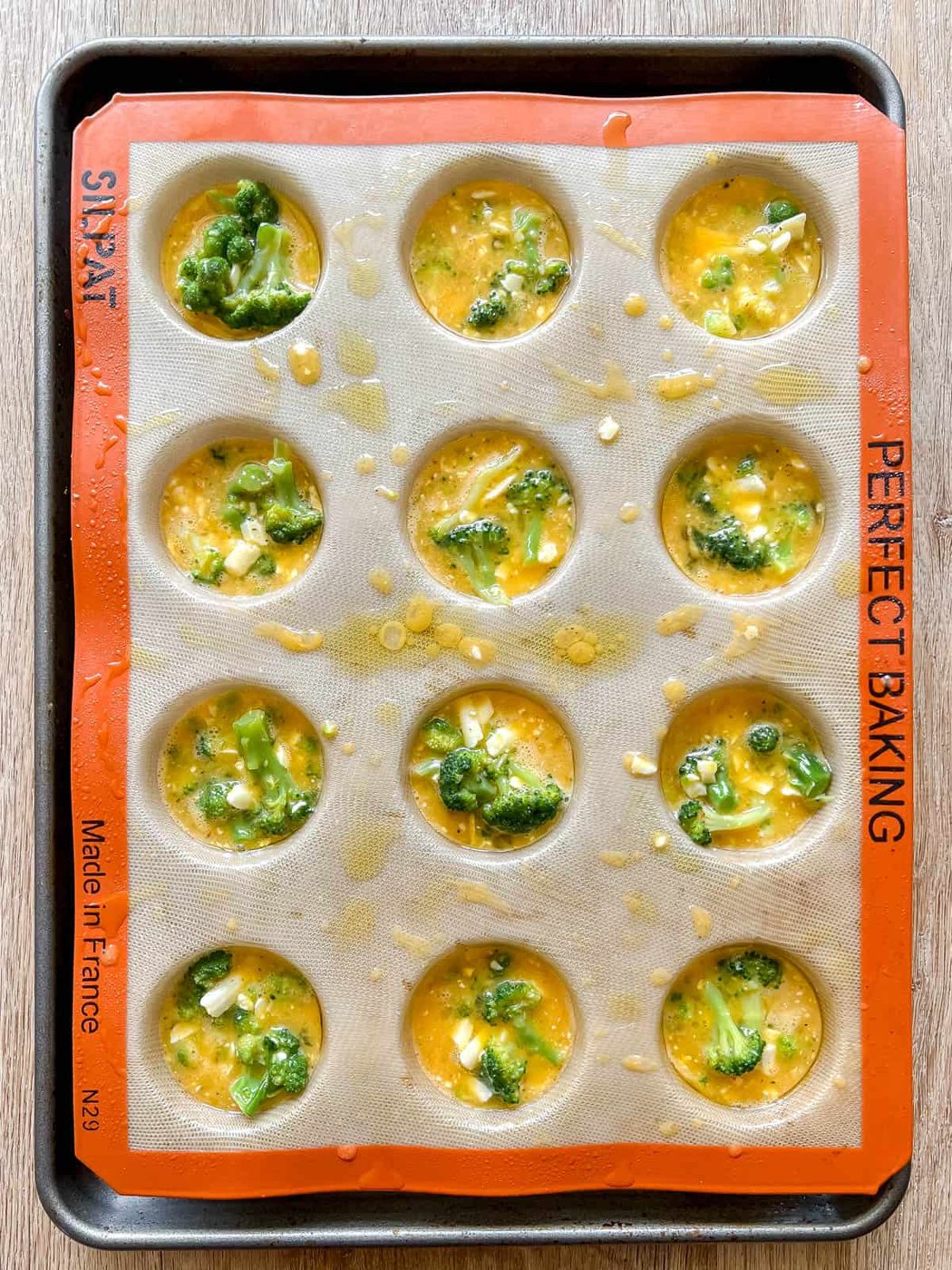 Broccoli egg muffin batter in egg tins.
