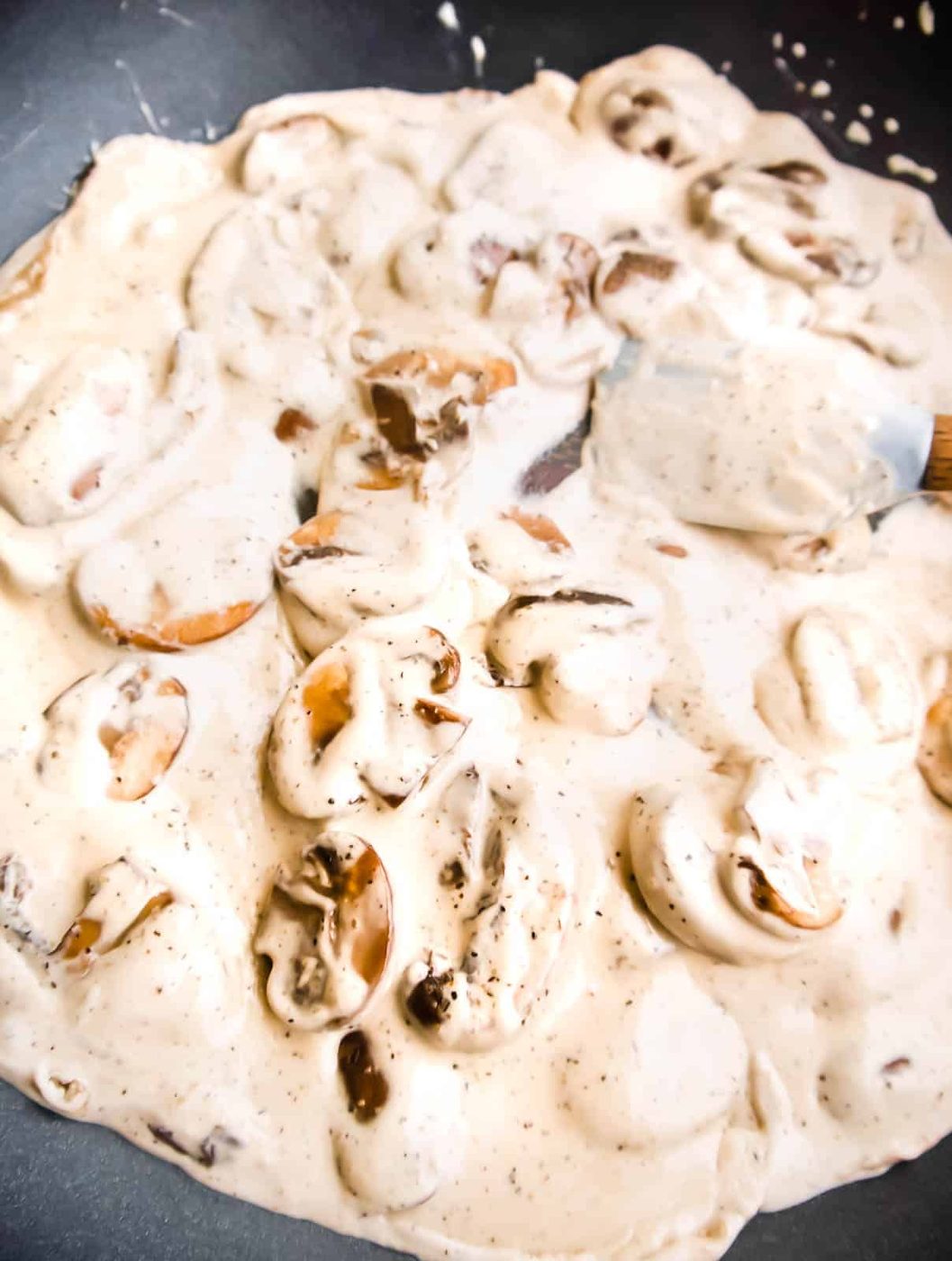 Coconut cream added to browned mushrooms in frying pan.