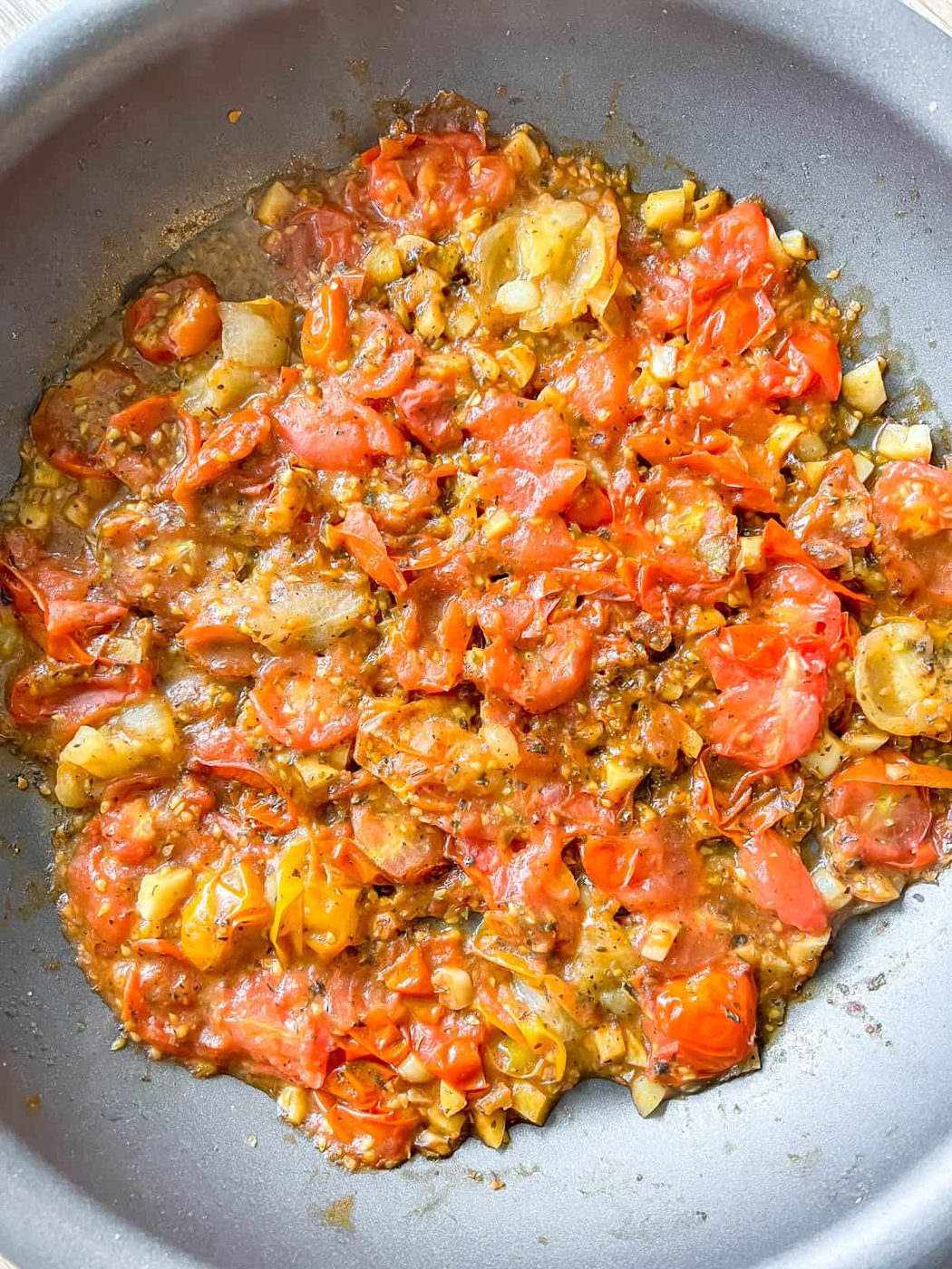 Cherry tomatoes, spices, herbs and garlic sautéed in pan.
