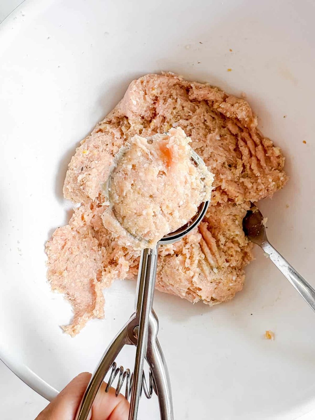 Rolling a meatball with a cookie scoop.
