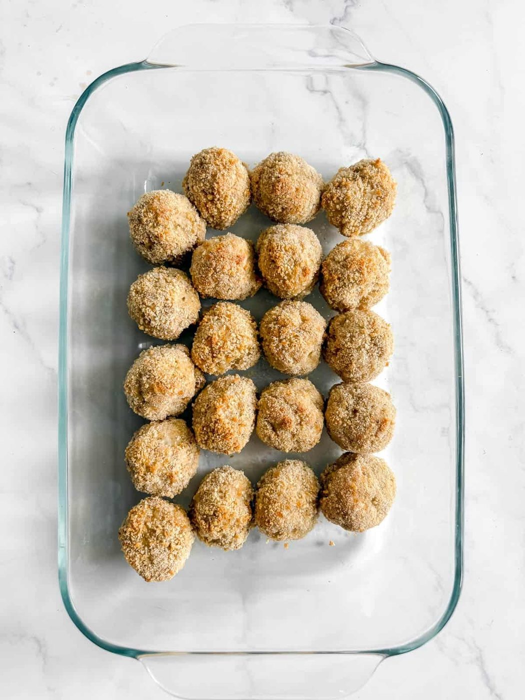 Chicken parmesan meatballs in a baking dish.