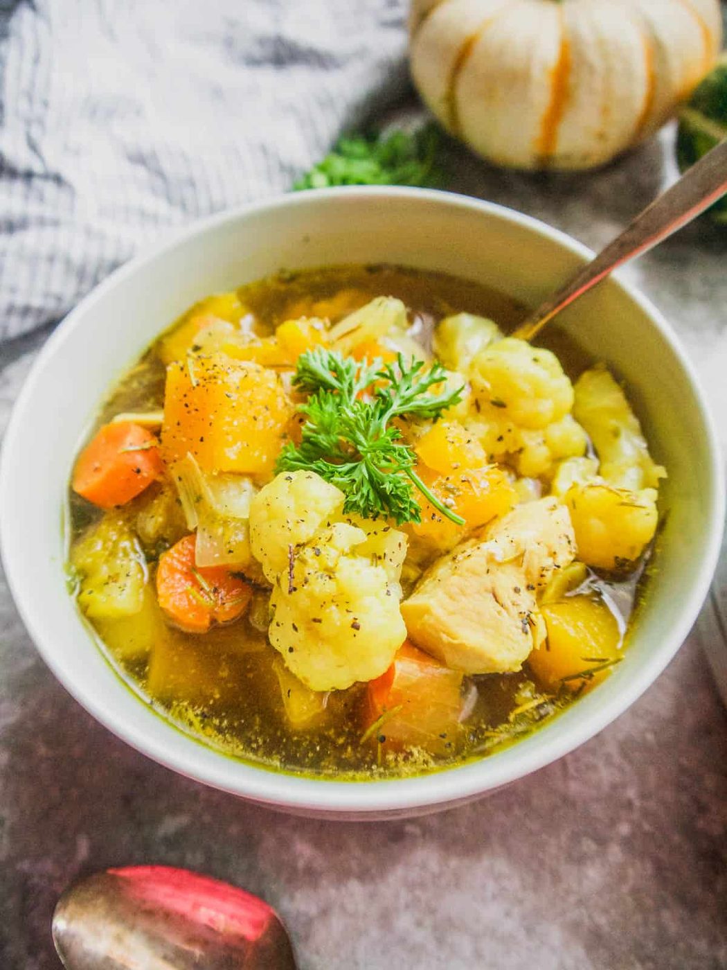 Carrot potato chicken soup in a bowl with parsley on top.