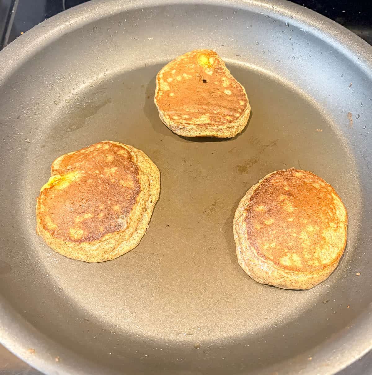 Flipping chia flax protein pancakes in a pan.