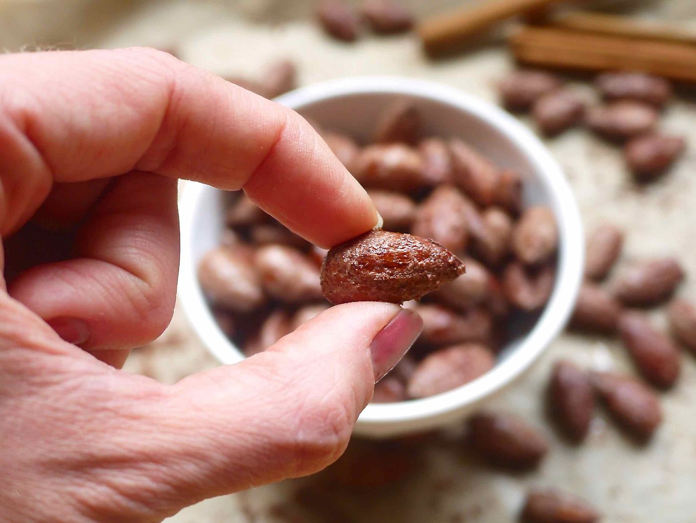 Fingers holding a cinnamon maple almond.