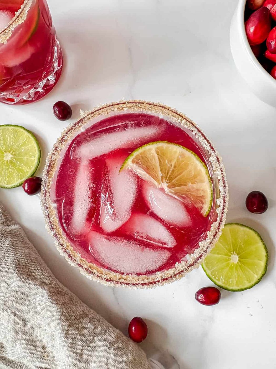 Cranberry lime margarita in a cup with ice.