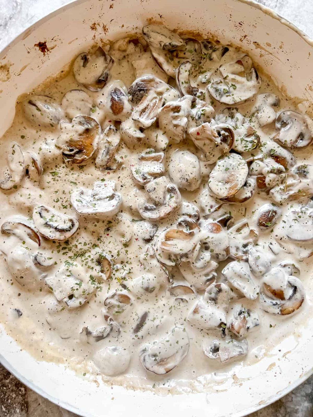 Coconut cream mixed into mushrooms in a pan.
