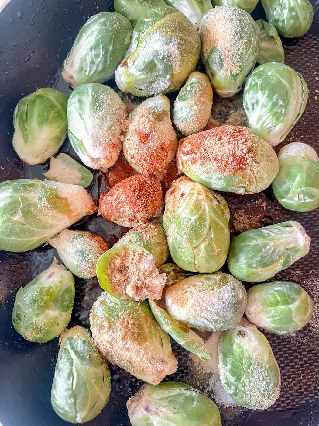 Brussels sprouts in a pan with seasoning on top.