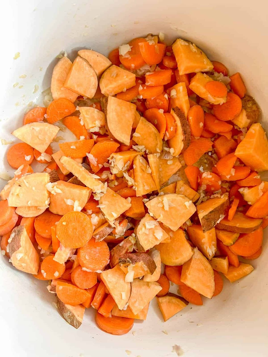 Carrots and sweet potatoes cooking in a pan.