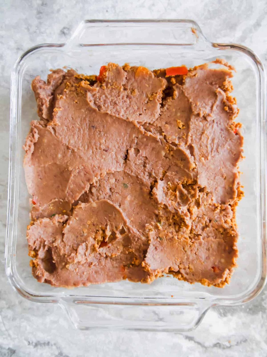Refried bean layer added to the pan.