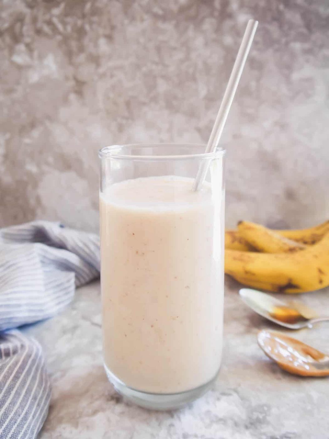 Banana maple smoothie in a glass with a straw.