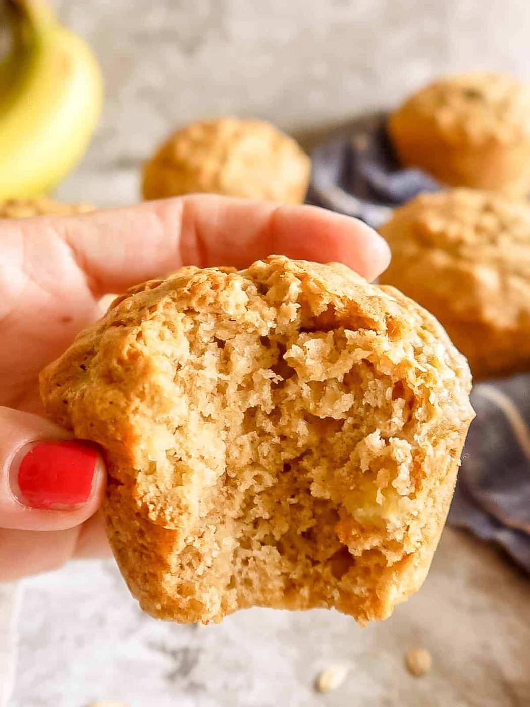 A bite taken out of a banana oatmeal muffin in ones hand.