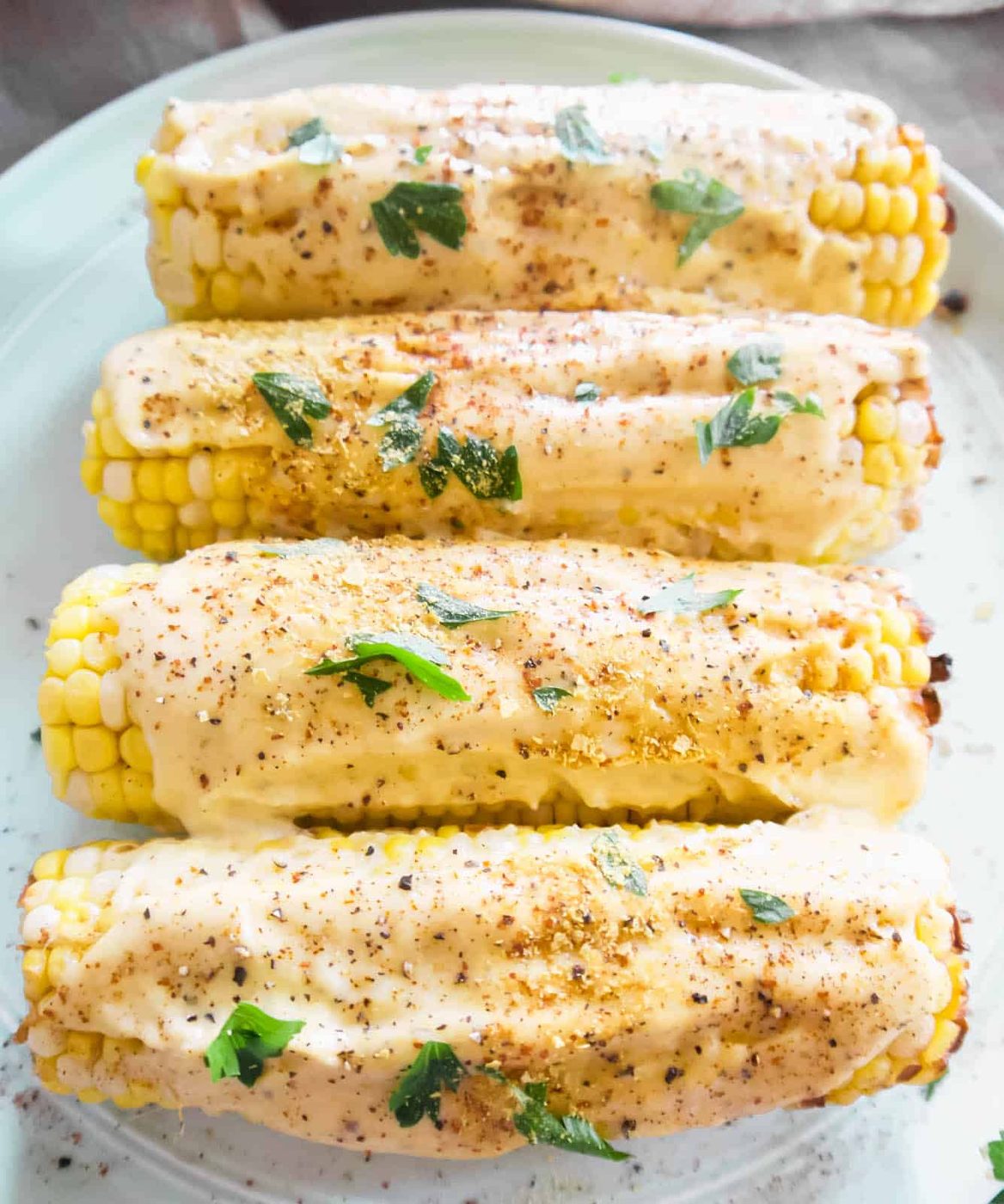 Vegan Mexican street corn elote on a plate with sauce on top.