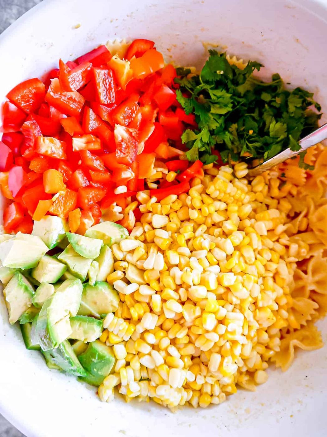 All of the ingredients on top of the pasta salad.