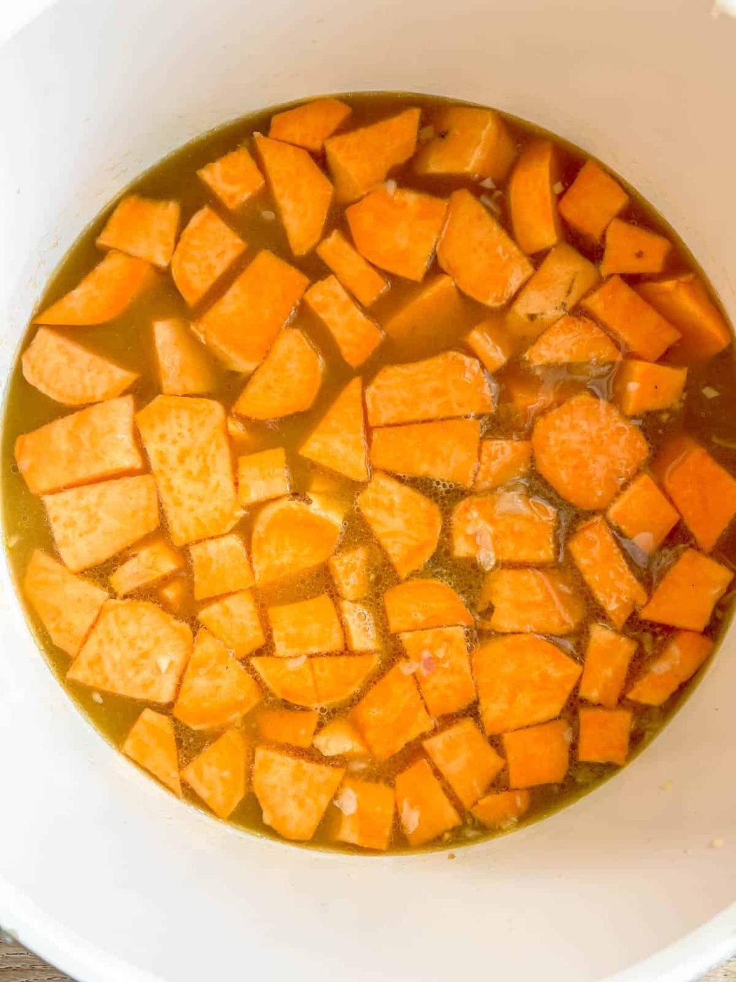 Sweet potatoes and bone broth boiling in a pan.
