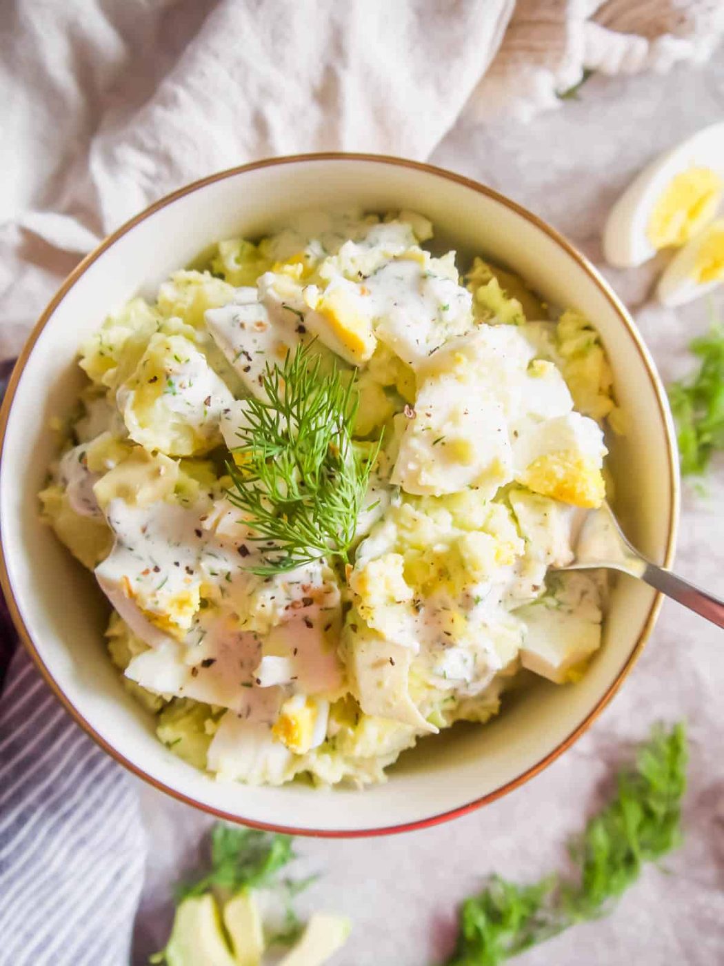 Avocado potato salad recipe in a bowl with a spoon in it.