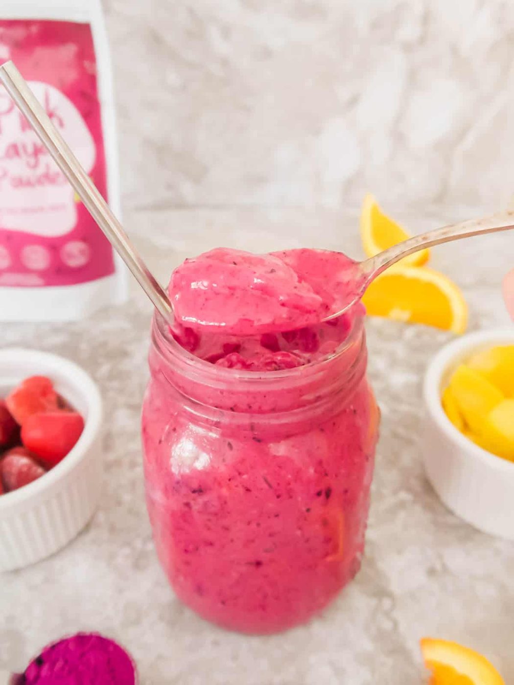 A scoop of a mango dragon fruit smoothie on a spoon.