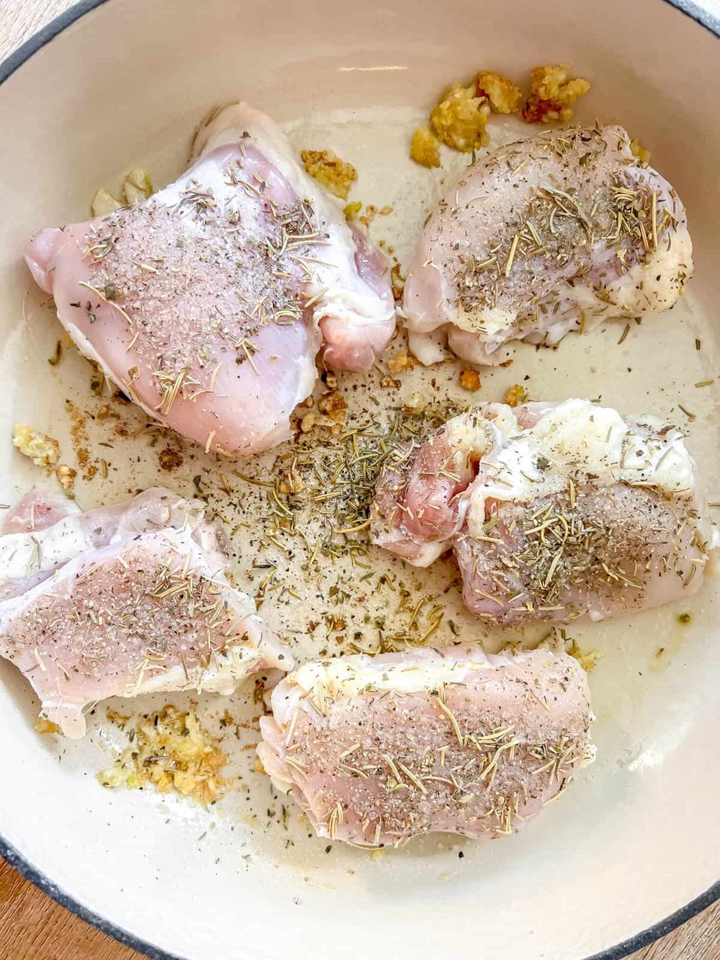 Chicken thighs added to a pan.