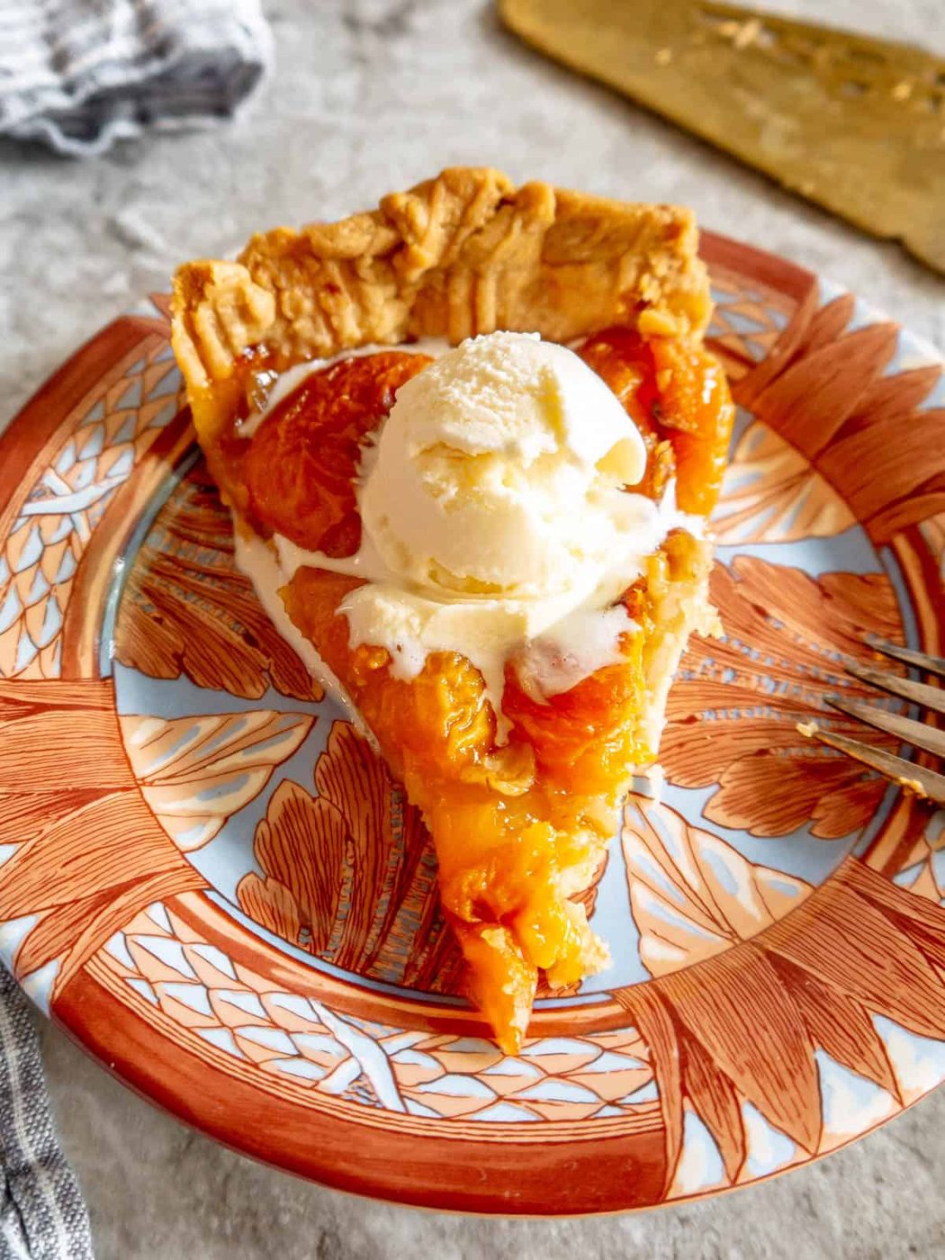 A slice of apricot tart with ice cream on top.