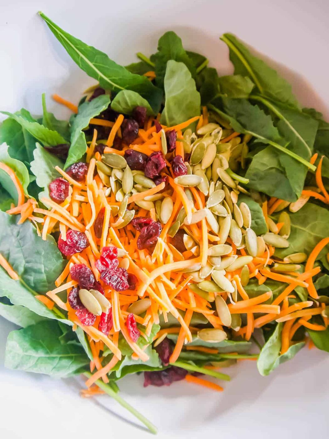 Kale, carrots and pumpkin seeds in a bowl.