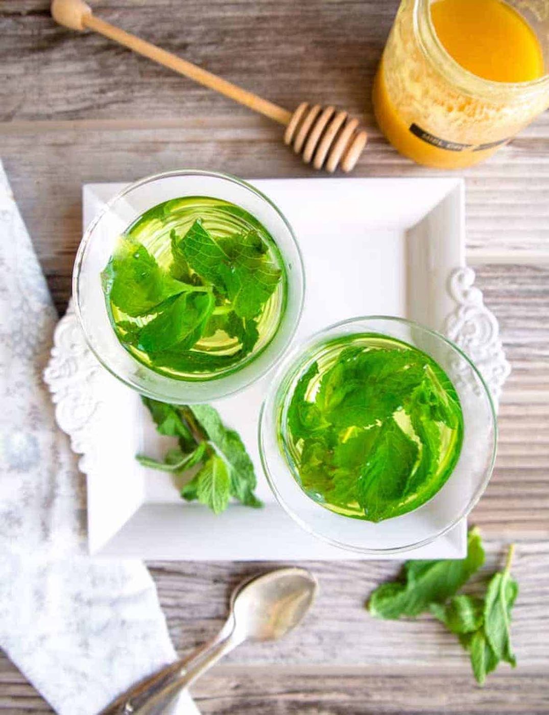 Two cups with mint tea leaves inside.
