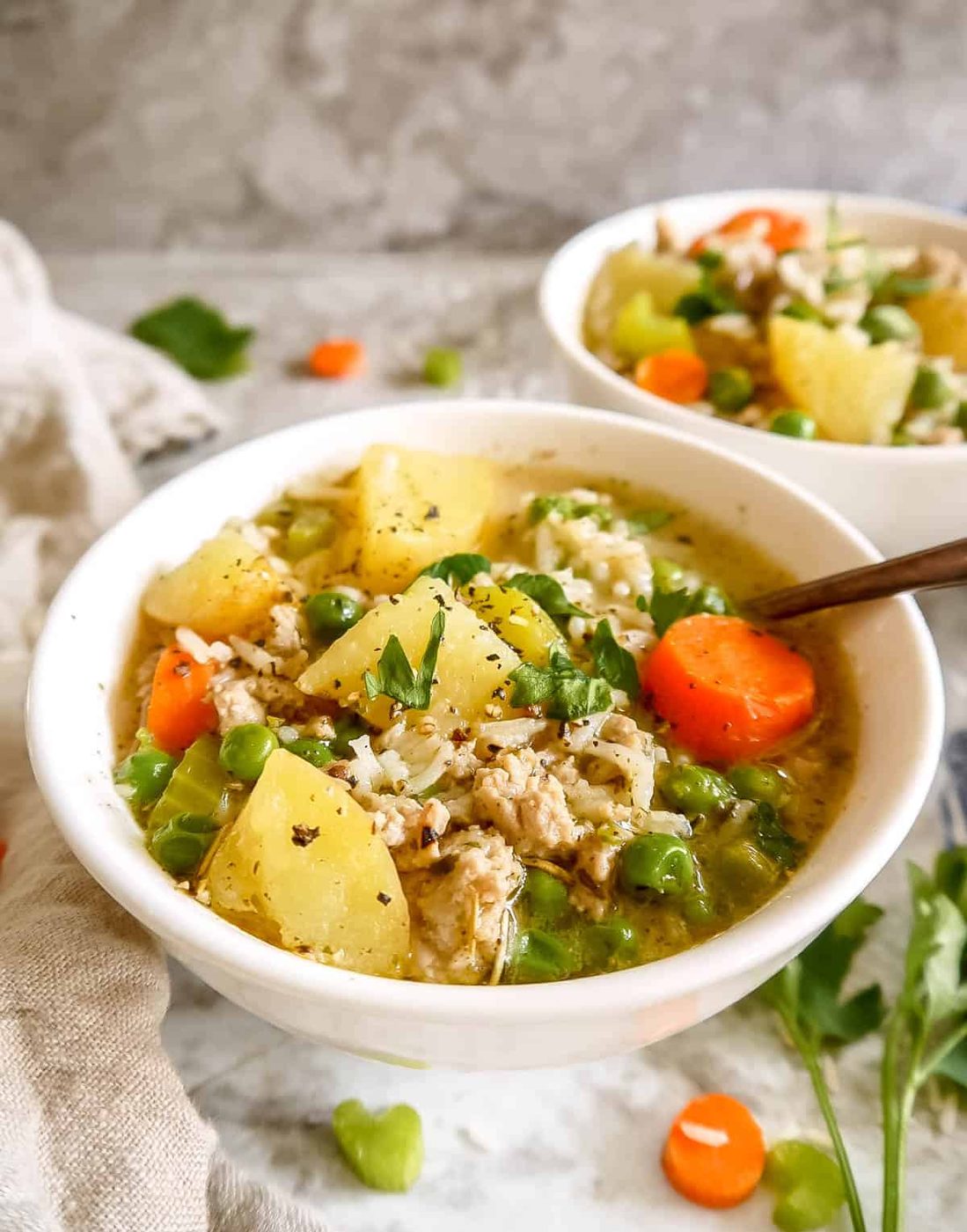Ground turkey rice soup in a two bowls with spoons in them.