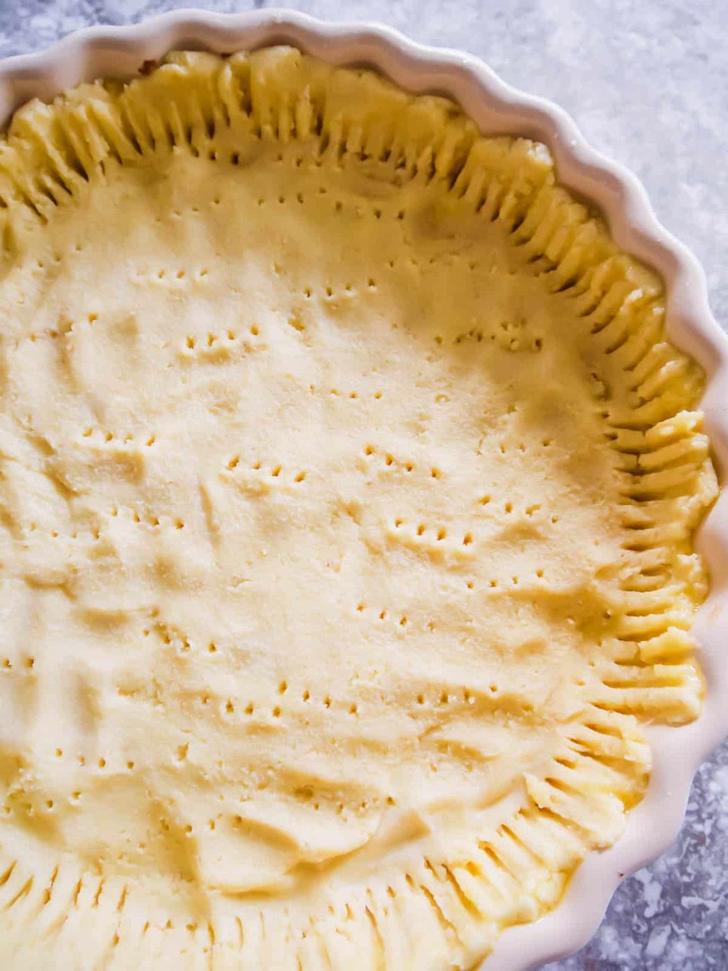 Paleo pie crust in a pan with holes poked in it.
