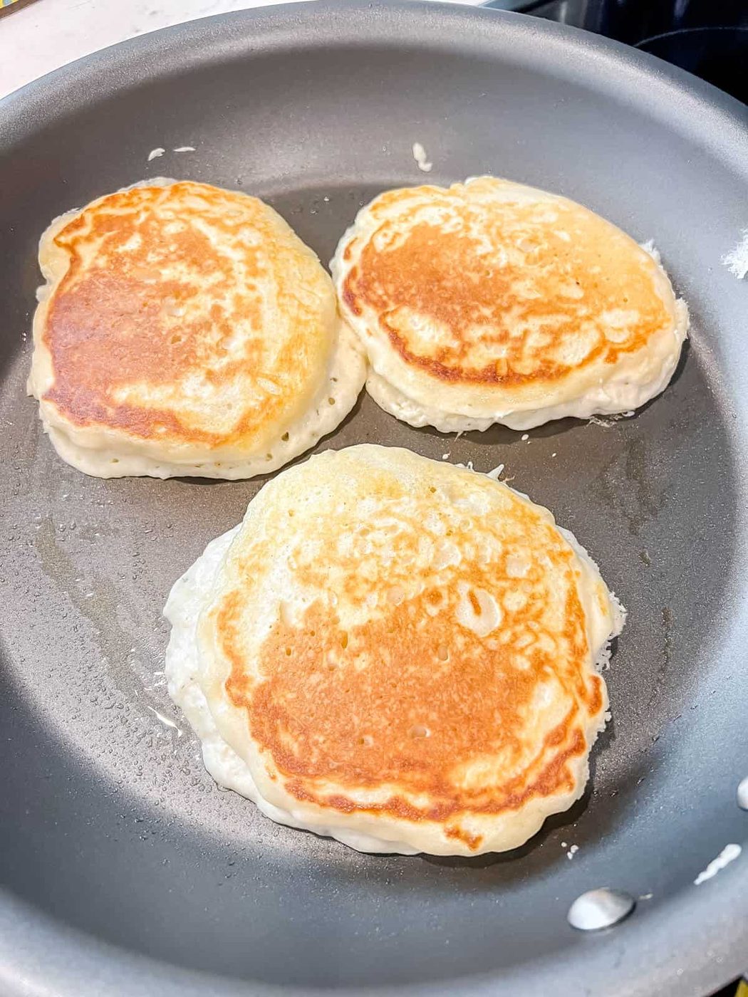 Greek yogurt pancakes after flipping on a pan.
