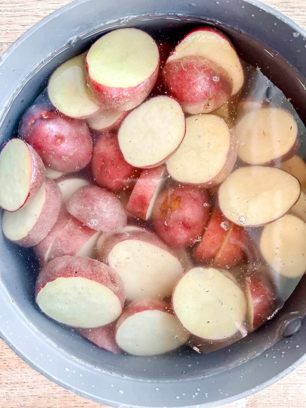 Sliced potatoes in a pan of water.