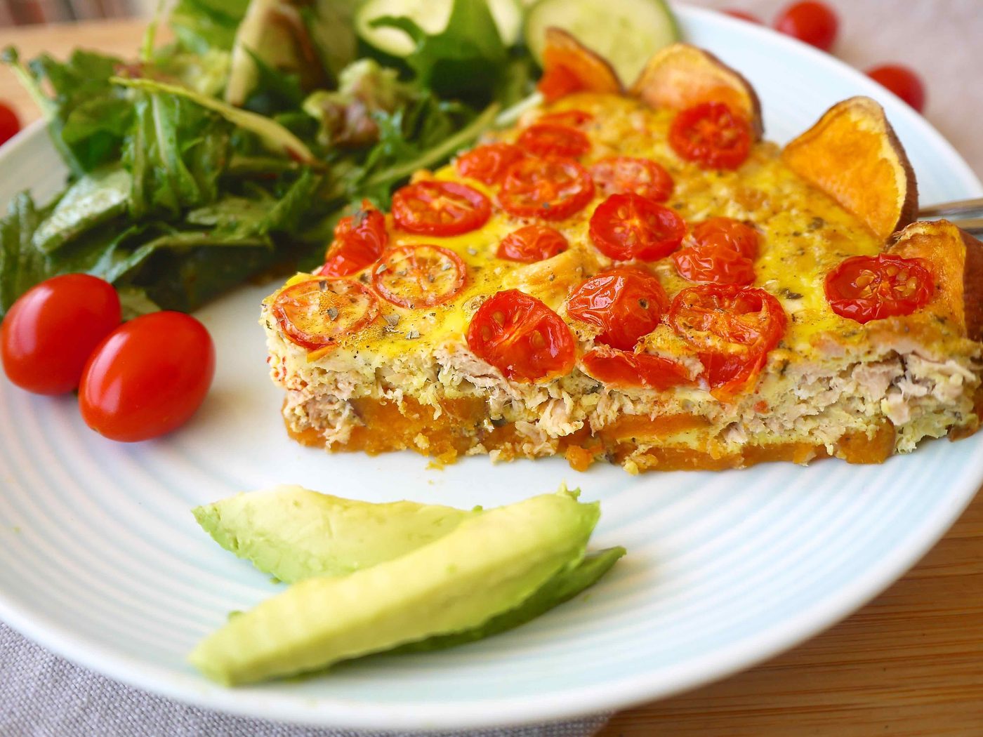A slice of a tuna and tomato quich e with a sweet potato crust on a plate.