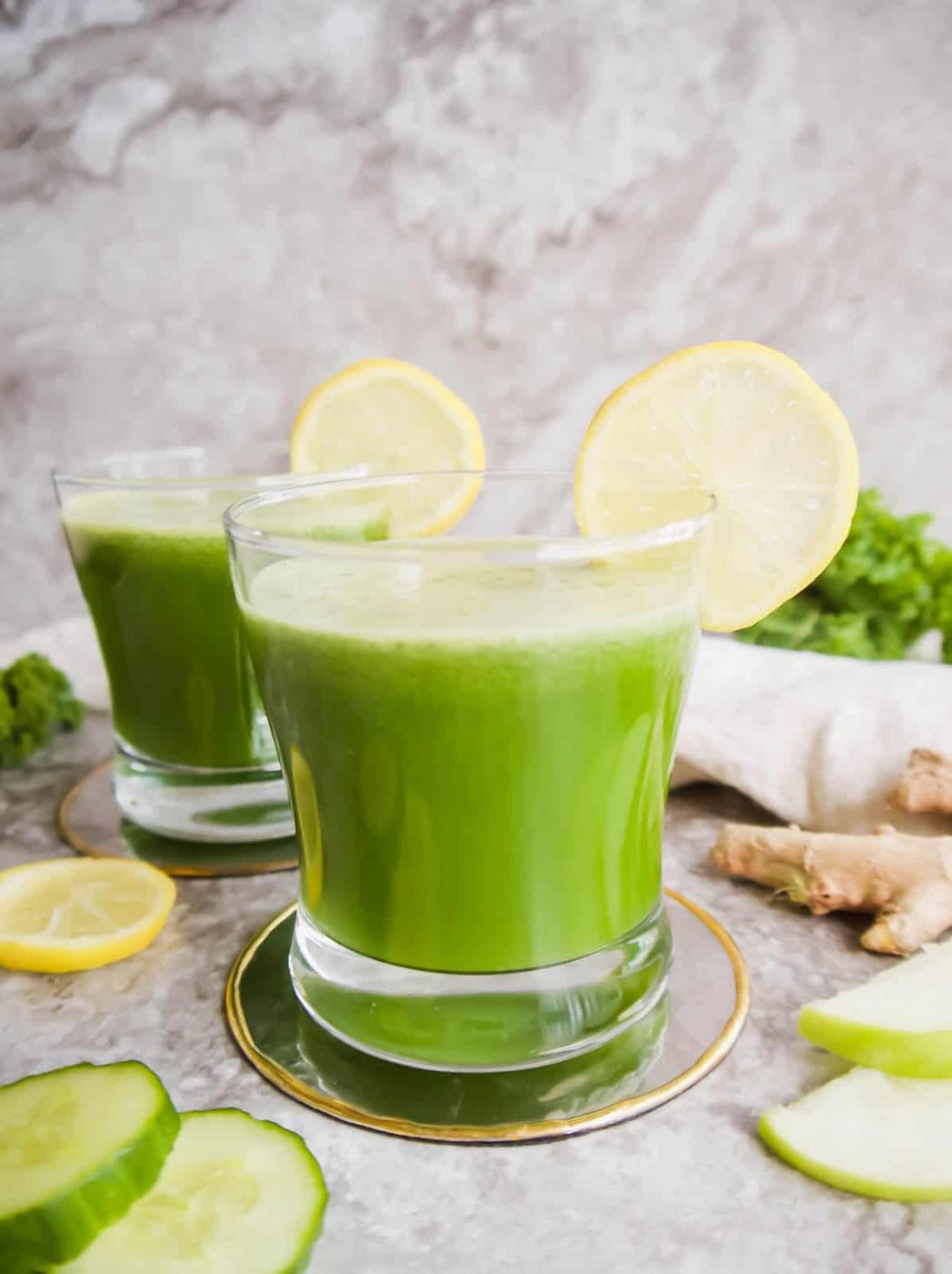 Two cups of Green Juice with Apple, Kale, Cucumber, Fennel, and Ginger.