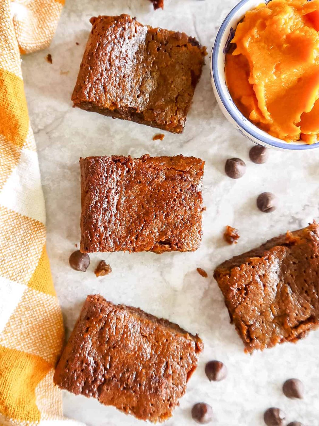 Lighter Pumpkin Brownies cut into pieces with chocolate chips surrounding them.