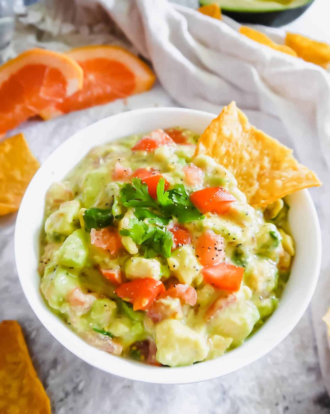 Citrus guacamole in a bowl with a chip inside.
