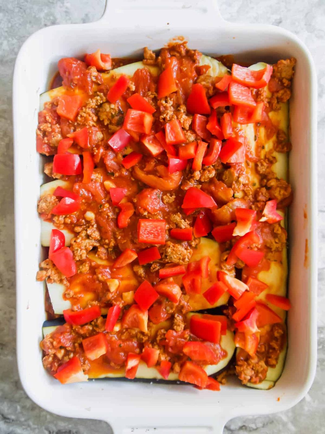 Red pepper and meat sauce layer added to the pan.