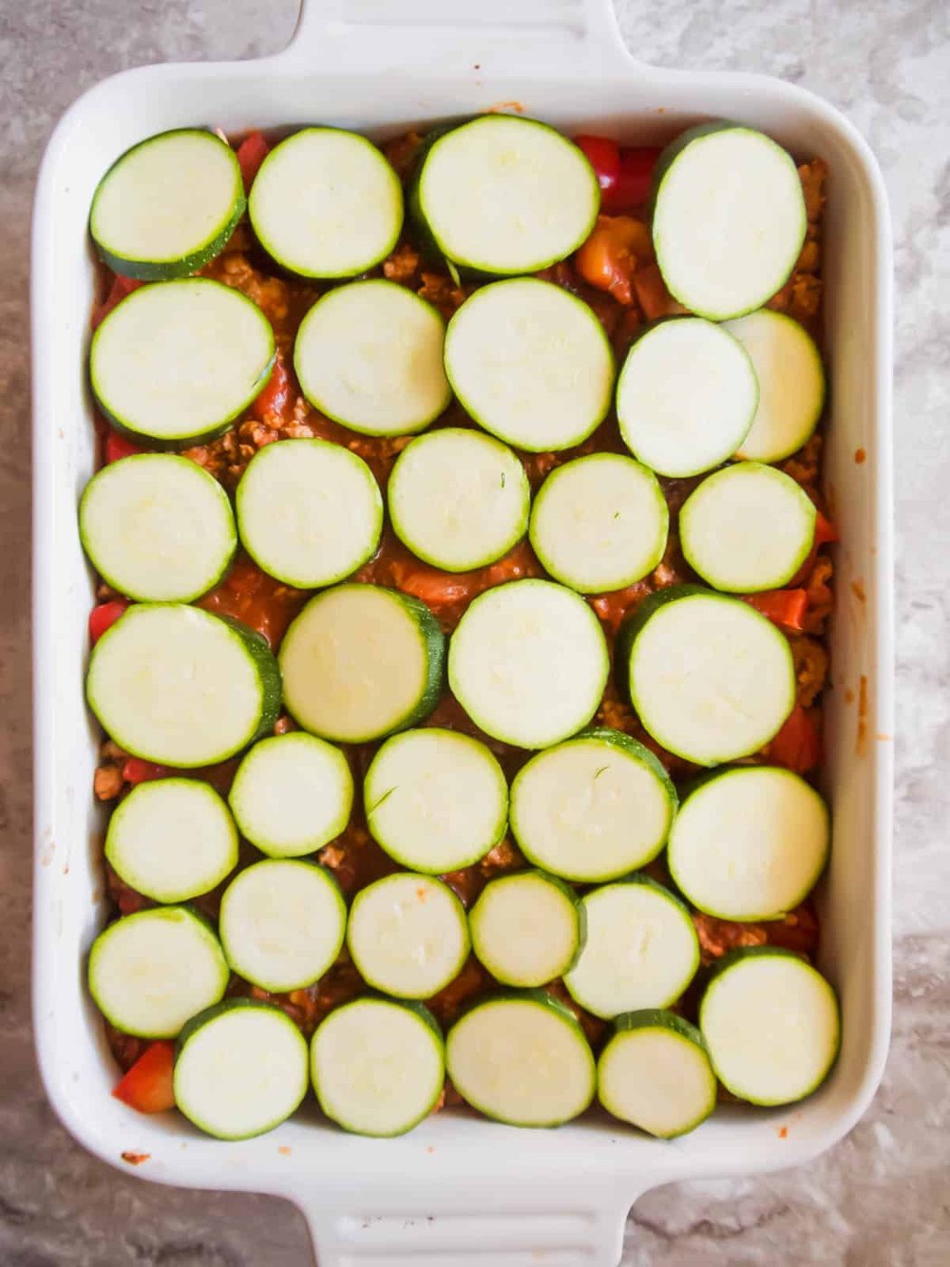 Zucchini layer added to the pan.