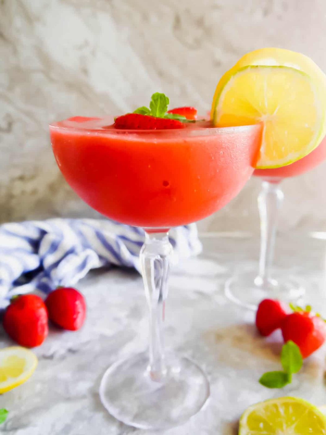The side angle of a lighter strawberry daiquiri recipe in a cocktail glass.