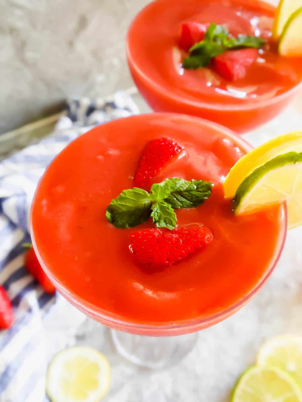 A beautiful lighter daiquiri made with strawberries in in two glasses.