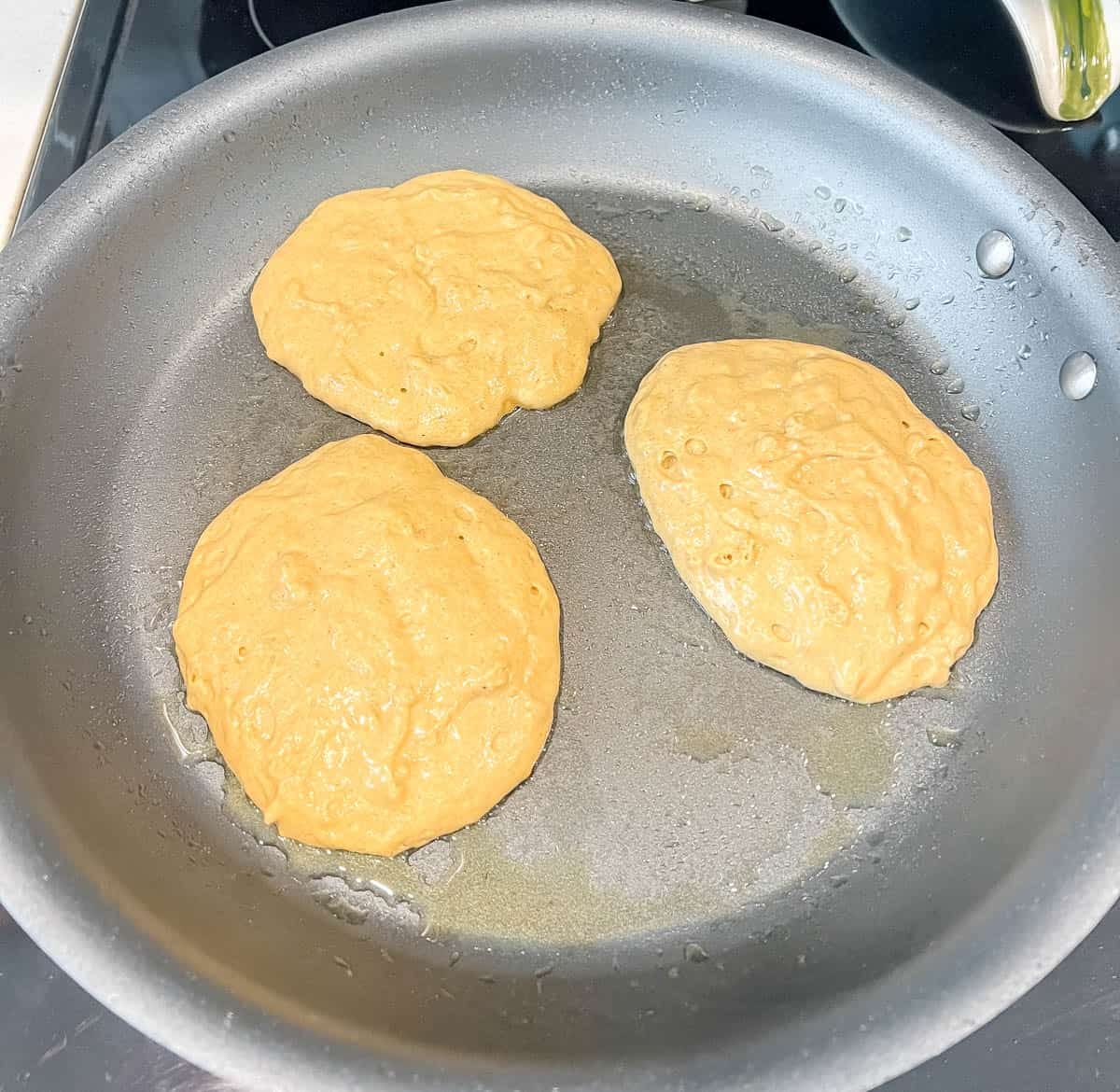 Lighter pumpkin pancakes on a pan.