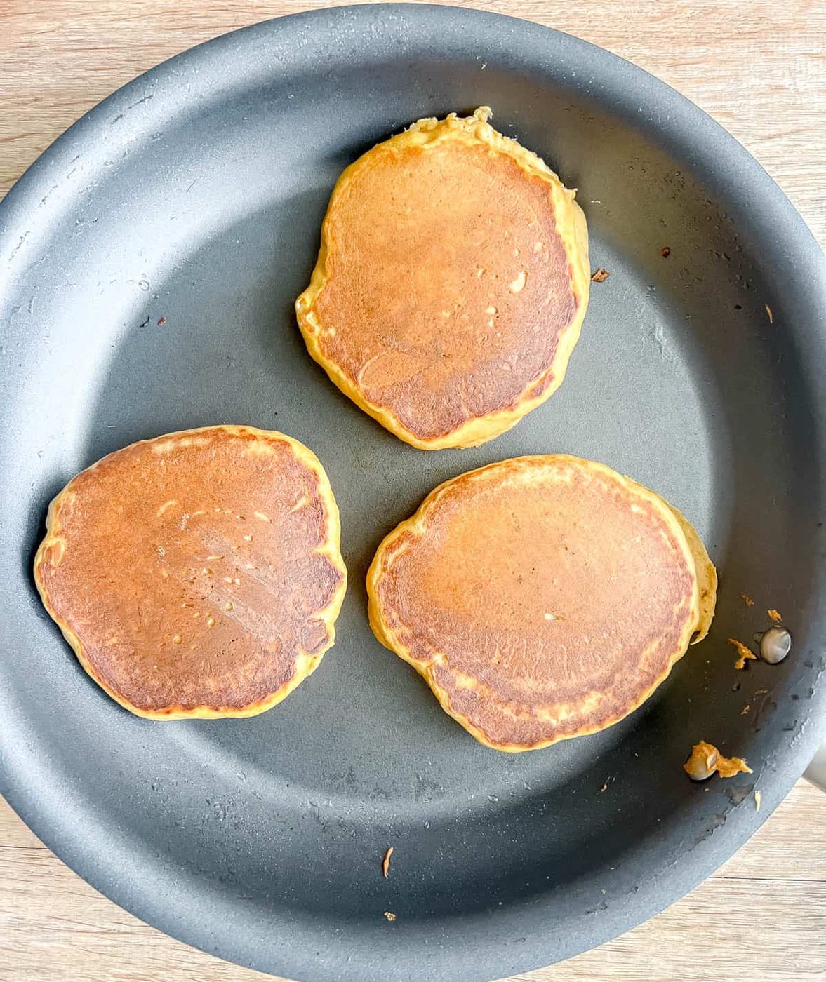 Lighter pumpkin pancakes flipped on a pan.