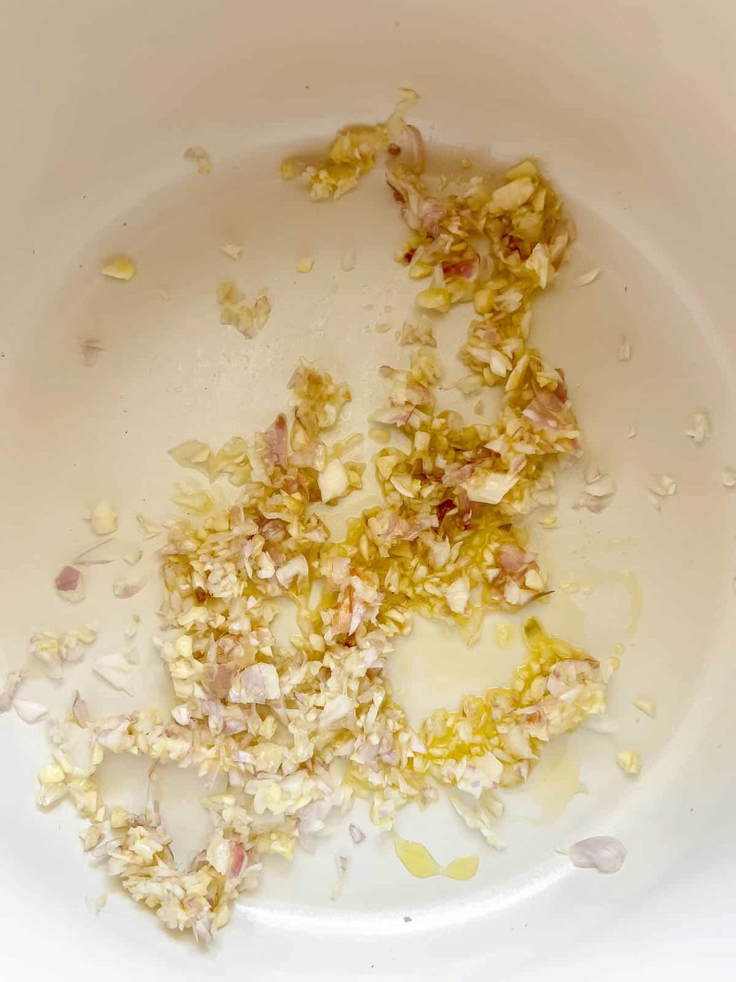 Onion and garlic in a pan being cooked.