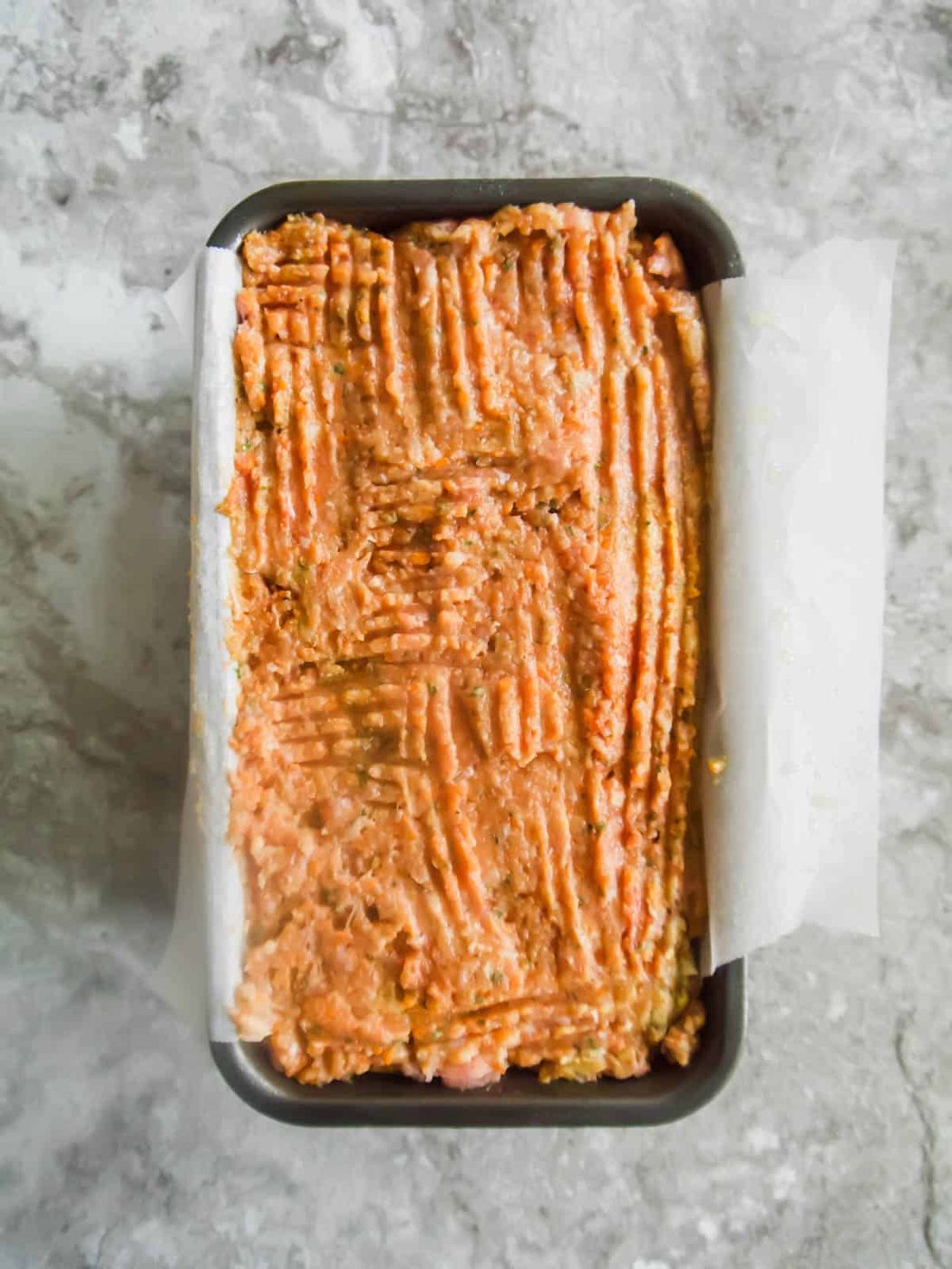 Meatloaf with ground turkey in a loaf tin before baking.