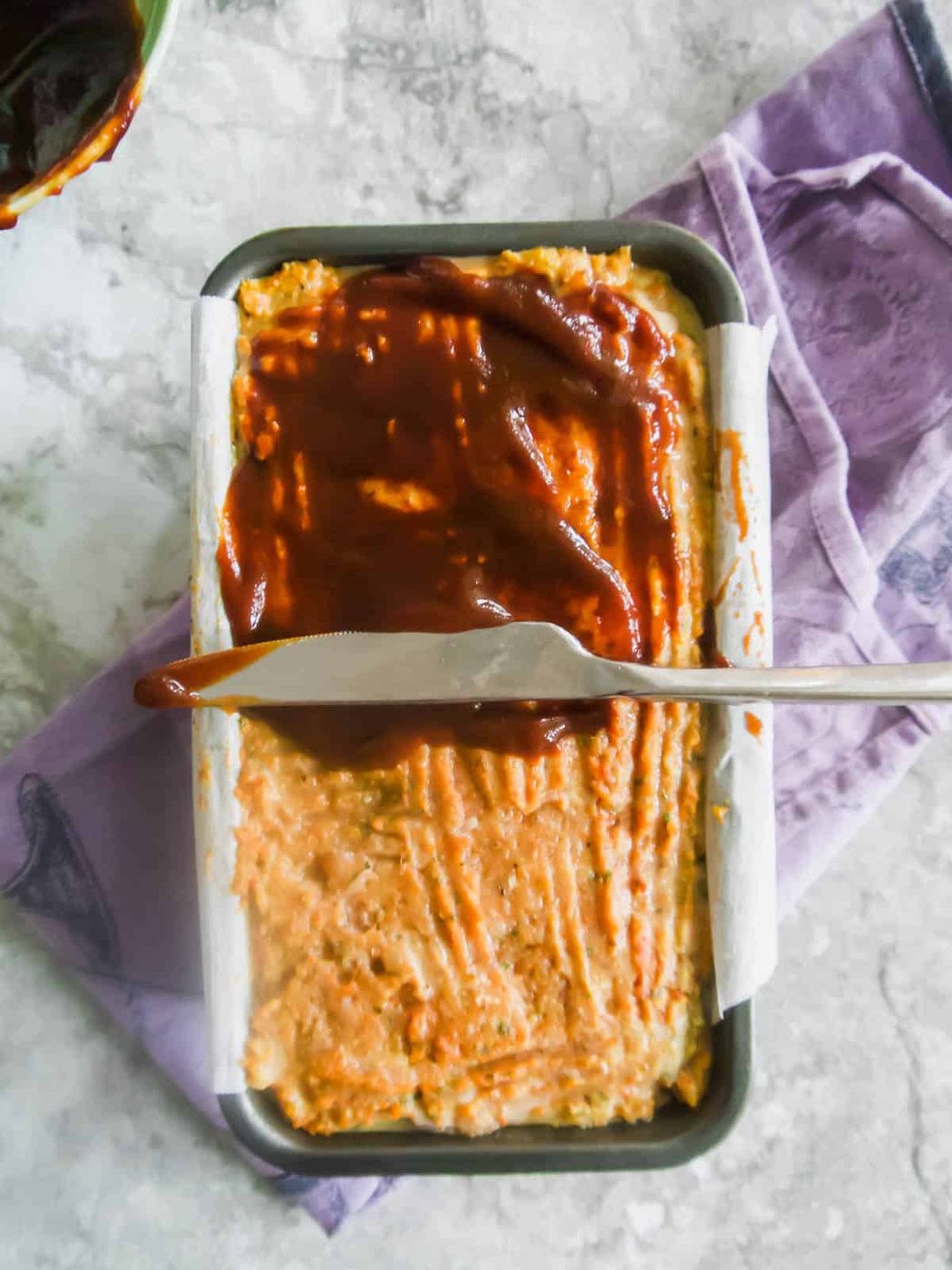 Meatloaf with ground turkey in a loaf tin with sauce on top before baking.